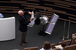 Astronaut Claude Nicollier explaining something with the help of a 1:10 scale model of the Hubble Space Telescope.