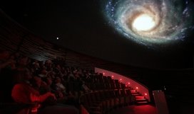 Der zentrale Hörsaal des Hauses der Astronomie, das Klaus Tschira-Auditorium mit 100 Sitzplätzen, verfügt über eine moderne Planetarium-Projektionsanlage, mit deren Hilfe die Besucher virtuelle Reisen durch den Weltraum unternehmen (hier: Außenansicht unserer Heimatgalaxie, der Milchstraße) sowie astronomisches Bildmaterial und Visualisierungen in Kuppelprojektion sehen können wie bei dieser Veranstaltung im September 2012. Bild: HdA/M. Pössel