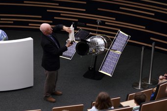 ESA astronaut Claude Nicollier explains one of his Hubble Space Telescope repair missions to elementary school students Astronaut Claude Nicollier explaining something with the help of a 1:10 scale model of the Hubble Space Telescope.