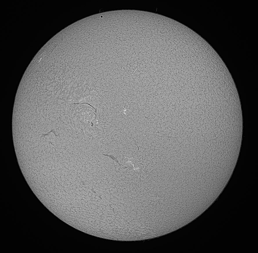 Black&white image of the transit of Mercury on 9 May 2016 as seen in H alpha. Mercury is visible as a small black dot near the upper rim of the Sun.