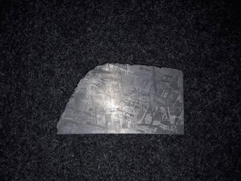 Shiny slice of an iron meteorite with a vertical stripe pattern overlaid by an oblique stripe pattern Shiny slice of an iron meteorite with a vertical stripe pattern overlaid by an oblique stripe pattern