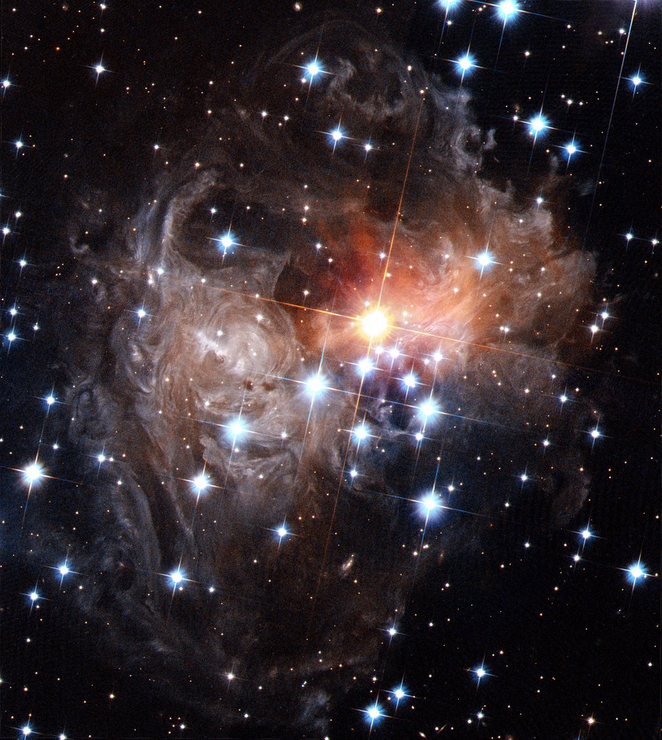 The reddish star V838 Monocerotis in September 2006 surrounded by greyish dust shreds, plus additional foreground stars