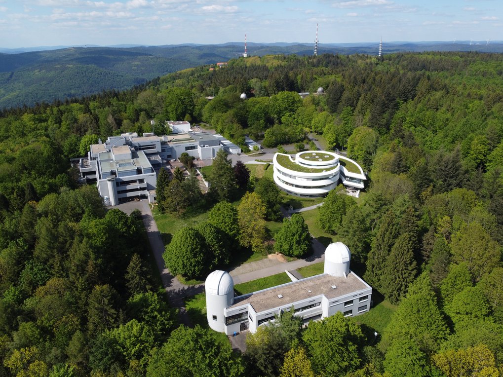 Luftaufnahme des MPIA-Campus bei blauem Himmel am 30. Mai 2022. Im Hintergrund die Landessternwarte und die auf dem Königstuhl platzierten Sendemasten.