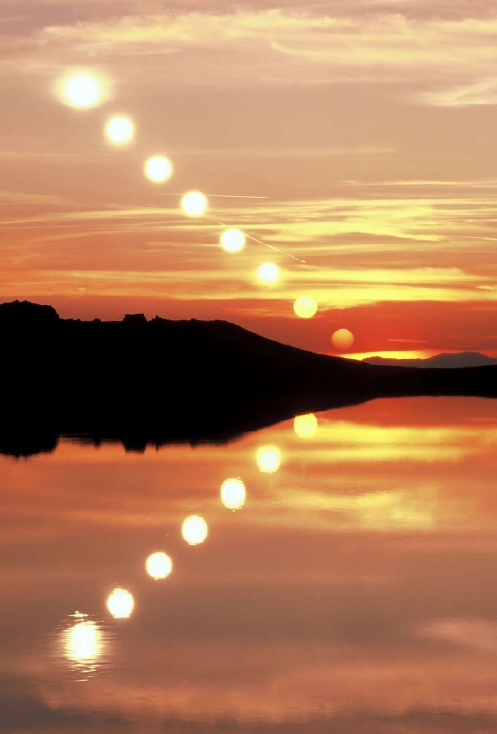 Zeitserie der untergehenden Sonne mit Spiegelung im Wasser. Die Helligkeit der Sonnenscheibe nimmt zum Horizont hin deutlich ab