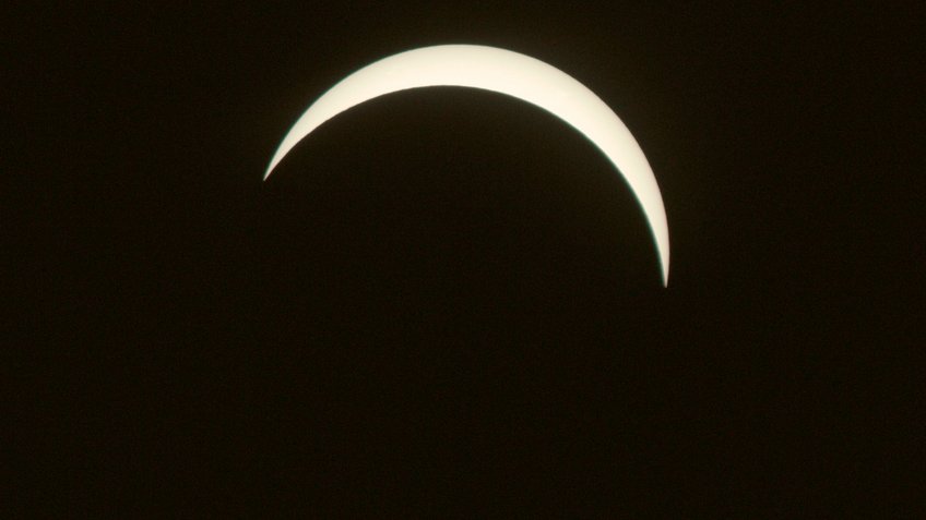 Foto einer partiellen Sonnenfinsternis, die in etwa mit der Konstellation von Sonne und Mond übereinstimmt, wie sie während der Sonnenfinsternis vom 12. August 2026 von Heidelberg zu sehen ist. Eine helle, schmale Sichel steht vor dunklem Hintergrund. Die Form zeigt eine partielle Sonnenfinsternis, bei der der Mond einen Teil der Sonne bedeckt. Die Konturen sind klar und gleichmäßig.